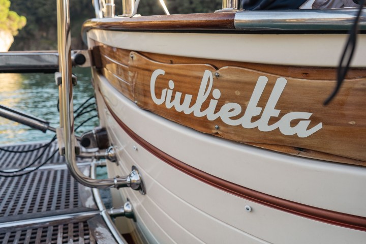 Close-up of a wooden boat named 'Giulietta' docked near water.