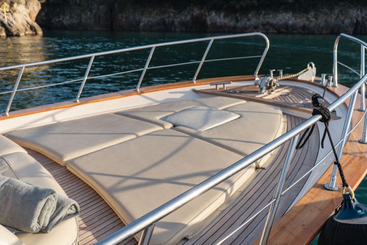 Luxury yacht deck with railings, sunbeds, and water view.