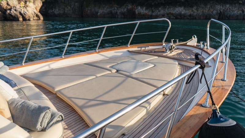 Luxury yacht deck with railings, sunbeds, and water view.