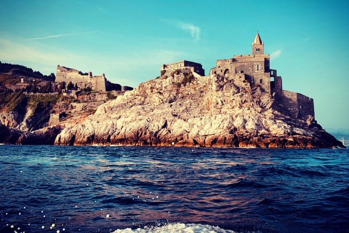 Stone fortress on rocky cliff by sea with blue sky background.