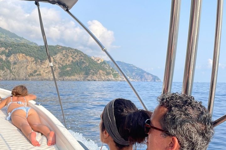 People relaxing on a boat with scenic cliffs and ocean in the background.