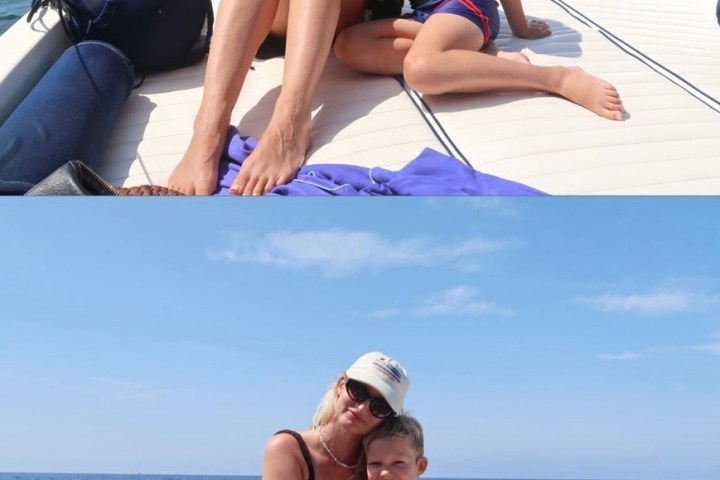 Woman and child on a boat, sitting together, with ocean and blue sky in background.