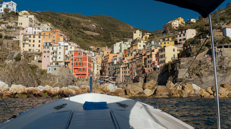 Colorful hillside village with houses viewed from a boat on the water.