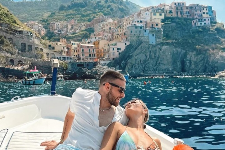 Couple relaxing on a boat with view of a coastal village on a hill.