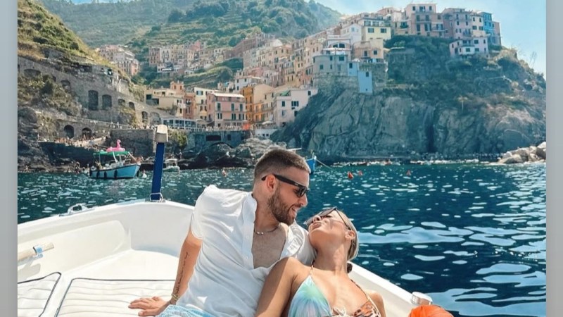 Couple relaxing on a boat with view of a coastal village on a hill.