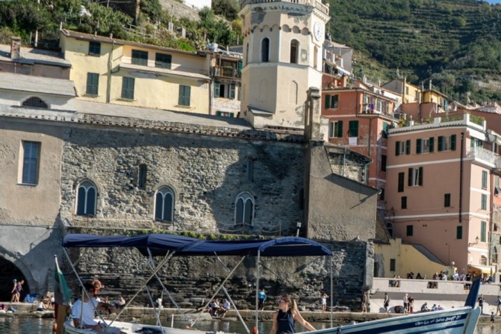 Boat named 'Princess' on water with colorful buildings and a bell tower in the background.