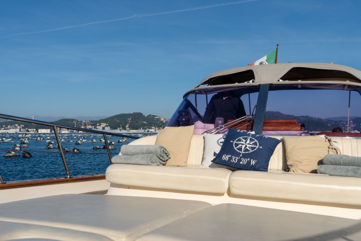 View from a yacht's deck with cushions, towel, and ocean scenery in the background.