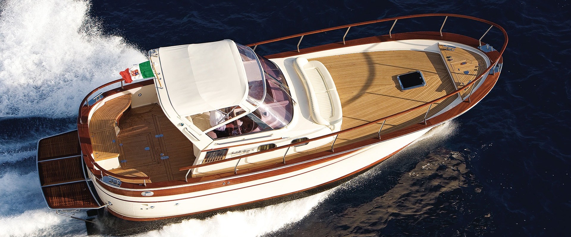 Aerial view of a luxury motorboat speeding on open water under sunny skies.